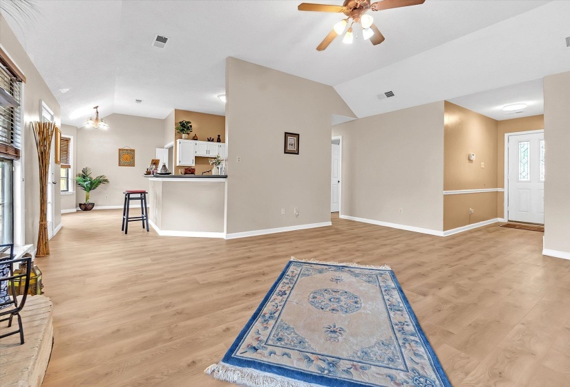 Unfurnished living room with healthy amount of natural light, vaulted ceiling, a ceiling fan, and light wood-type flooring