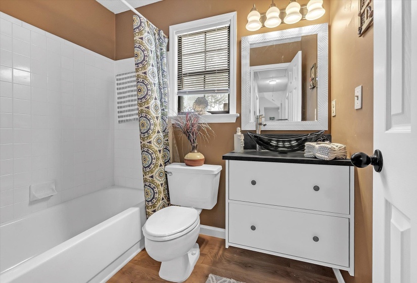 Bathroom featuring vanity, shower / tub combo, and dark wood finished floors