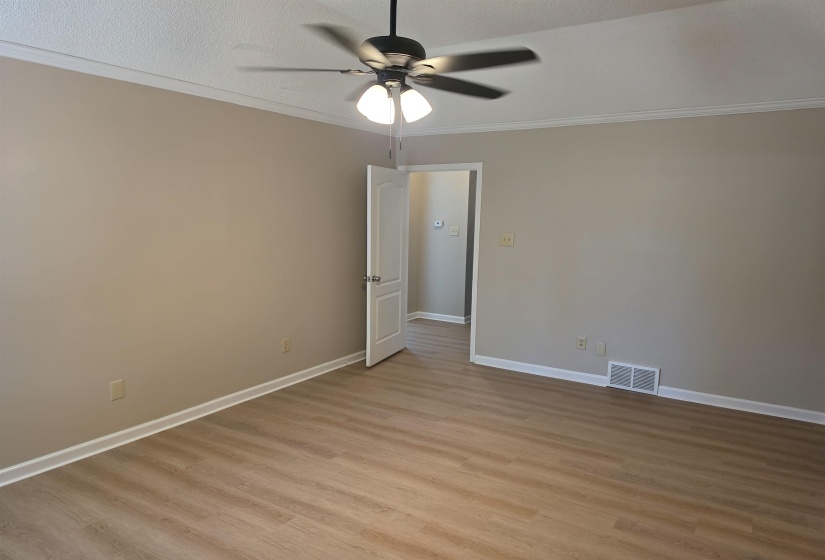 Crown molding, a ceiling fan, and light wood-style flooring, new paint