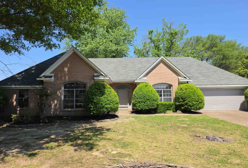 View of front of house featuring a front yard, brick siding, an attached garage, and driveway