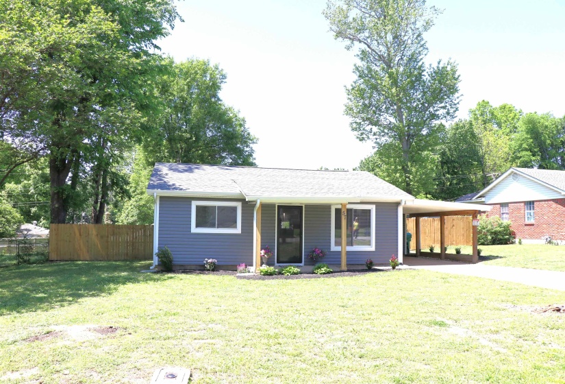 View of front of house featuring an attached carport, roof with shingles, and a porch