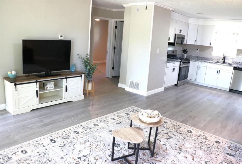 Living room featuring light wood-style floors, crown molding, and a textured ceiling