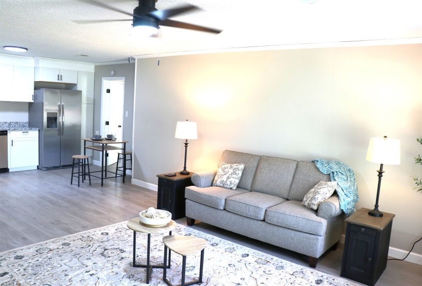 Living room featuring crown molding, a ceiling fan, light wood-type flooring, and a textured ceiling