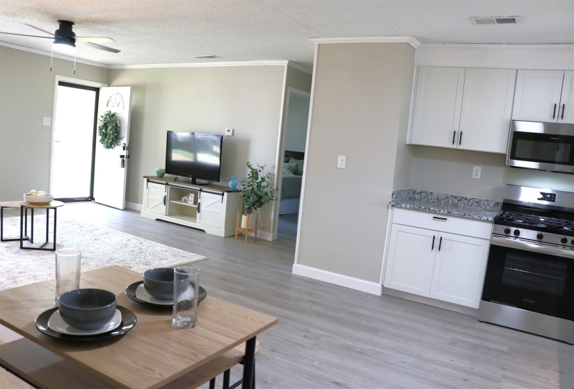 Kitchen featuring stainless steel appliances, white cabinets, light stone counters, a ceiling fan, and a textured ceiling