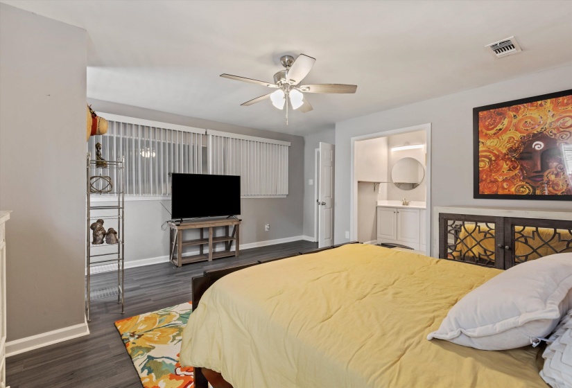 Bedroom featuring connected bathroom, dark wood-style floors, and a ceiling fan
