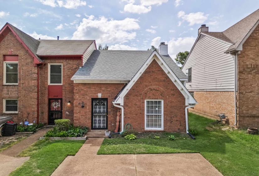 View of front facade featuring a front yard, roof with shingles, and brick siding