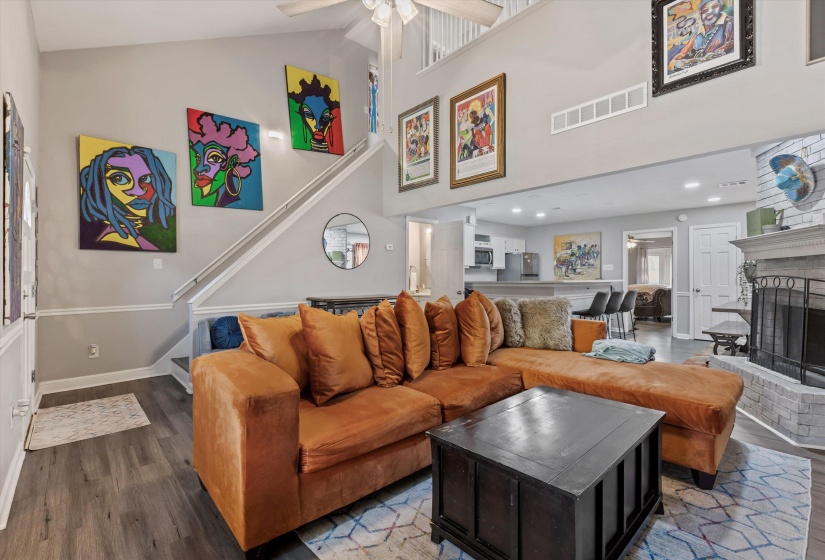 Living area featuring a fireplace, wood finished floors, ceiling fan, a high ceiling, and recessed lighting