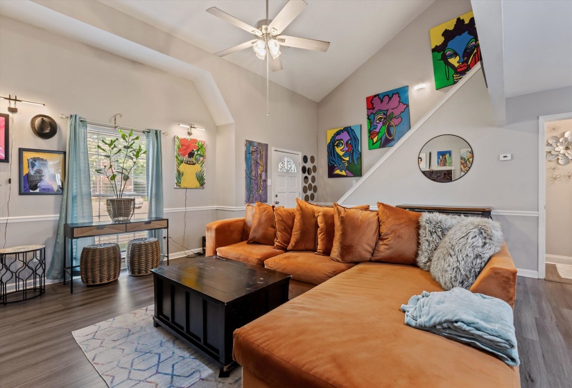 Living area featuring a ceiling fan, wood finished floors, and lofted ceiling