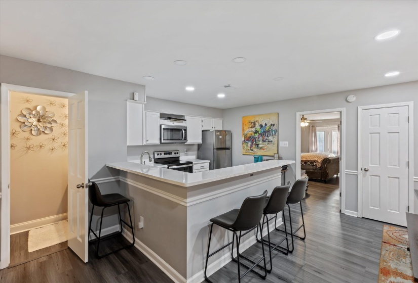 Kitchen featuring a breakfast bar area, stainless steel appliances, a peninsula, dark wood-style floors, and white cabinetry