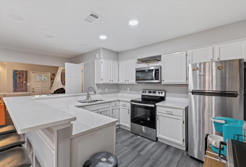 Kitchen featuring stainless steel appliances, a peninsula, a breakfast bar, white cabinets, and dark wood finished floors