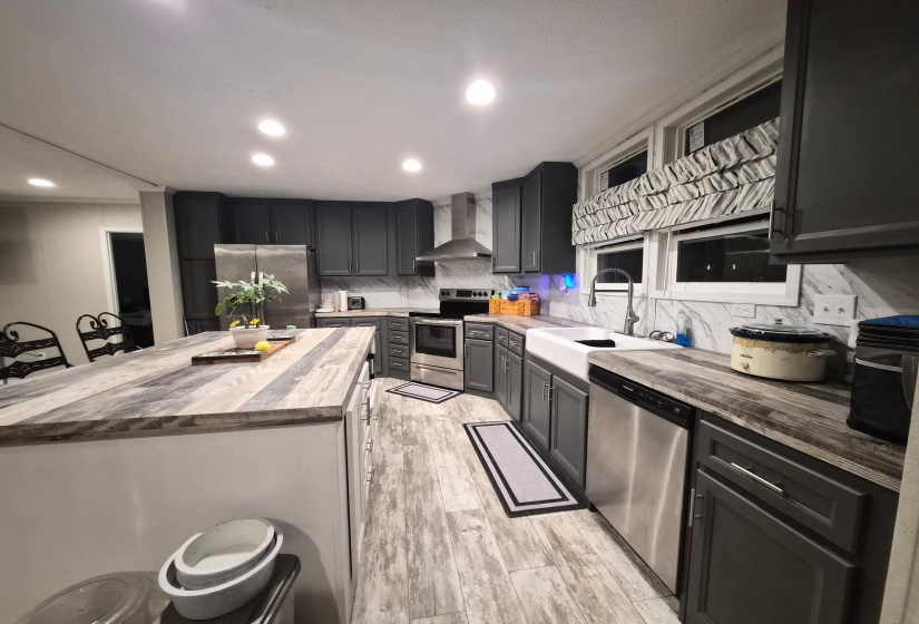 Kitchen with wooden counters, stainless steel appliances, backsplash, a kitchen island, and light wood finished floors