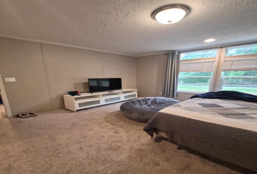Carpeted bedroom featuring a decorative wall, a textured ceiling, and ornamental molding