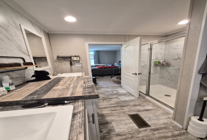 Full bath featuring vanity, connected bathroom, a marble finish shower, light wood-style flooring, and recessed lighting