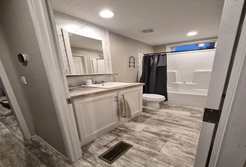 Bathroom featuring vanity, shower / tub combo with curtain, light wood-style floors, and recessed lighting