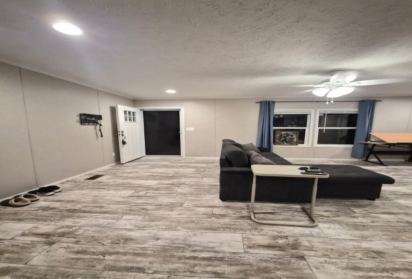 Living area with light wood-type flooring, recessed lighting, a ceiling fan, and a textured ceiling