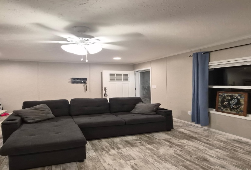 Living area featuring wood finished floors, a ceiling fan, crown molding, and recessed lighting