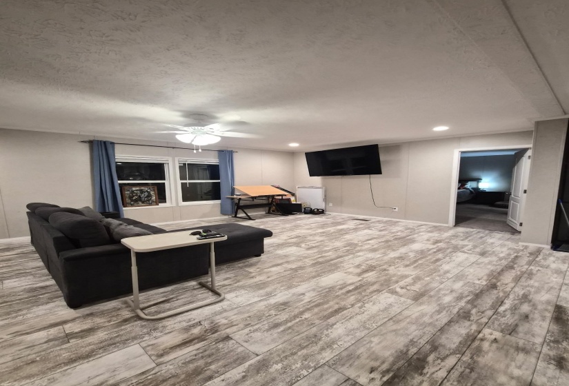 Living room with light wood finished floors, a ceiling fan, recessed lighting, and a textured ceiling