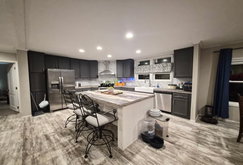 Kitchen with tasteful backsplash, stainless steel appliances, light wood-style flooring, a kitchen breakfast bar, and ornamental molding