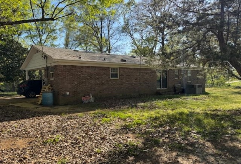 Back of property with brick siding and an attached carport
