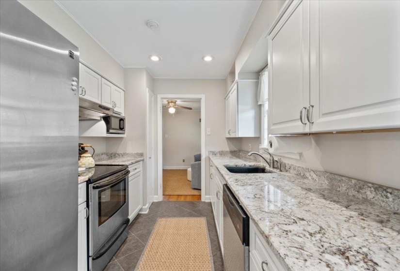 Kitchen with appliances with stainless steel finishes, white cabinetry, light stone countertops, and recessed lighting