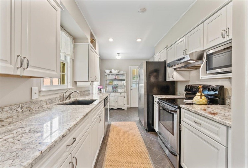 Kitchen featuring appliances with stainless steel finishes, white cabinets, recessed lighting, and light stone counters