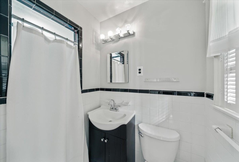 Bathroom with healthy amount of natural light, a stall shower, vanity, tile walls, and wainscoting