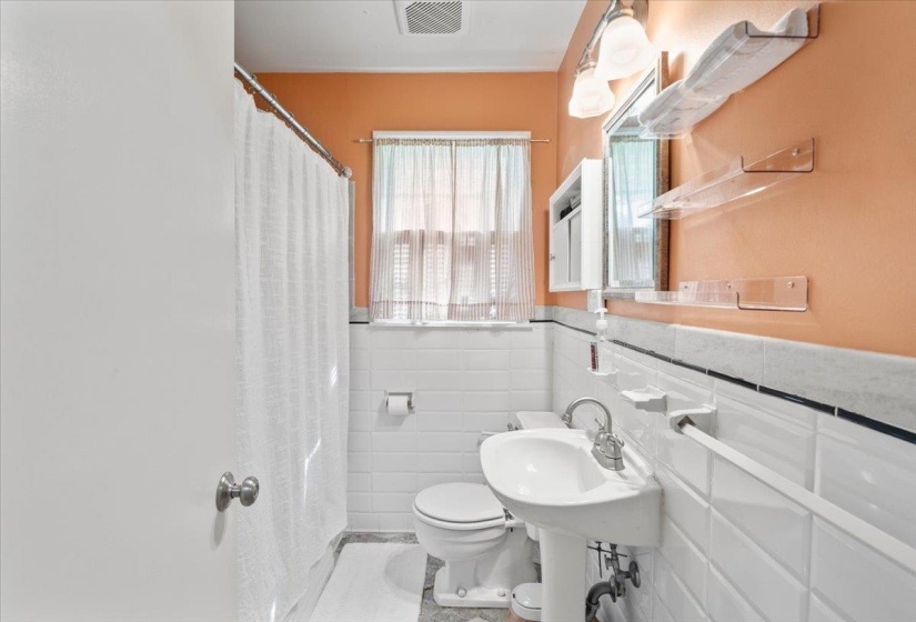 Full bath with a shower with curtain, tile walls, and wainscoting