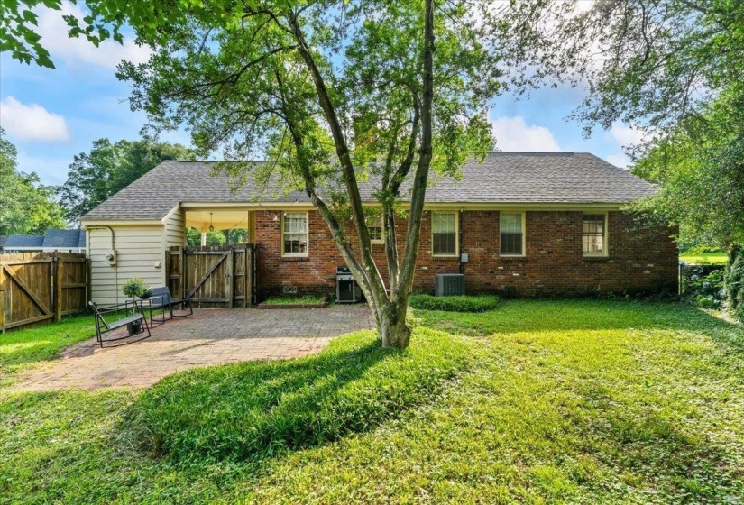 Back of house with a gate, a patio, and brick siding