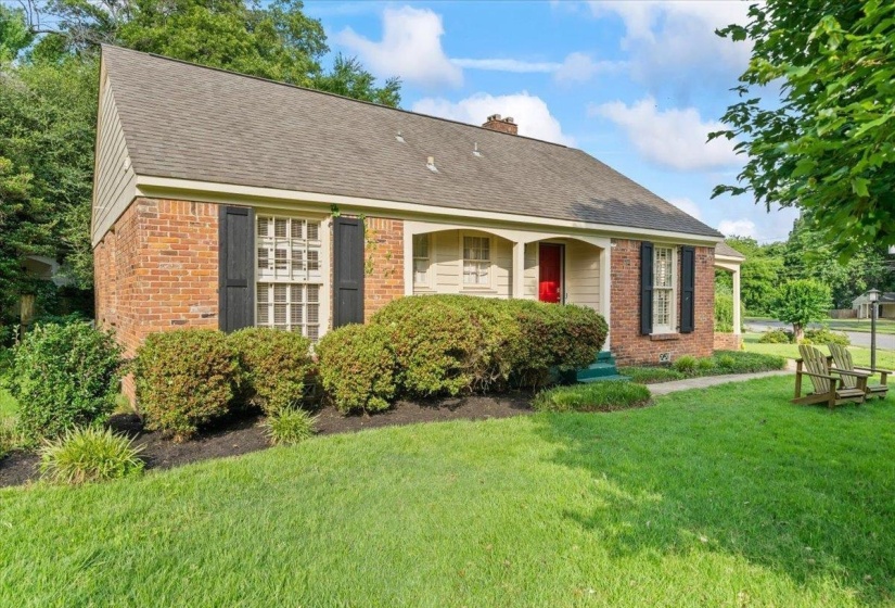 View of front of home with brick siding, a front yard, a shingled roof, and a chimney