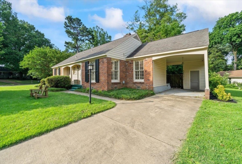 Ranch-style home with a front yard, concrete driveway, an attached carport, brick siding, and a shingled roof