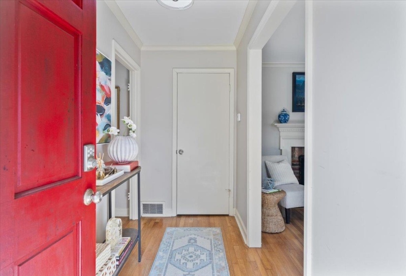 Foyer entrance with light wood-style floors, crown molding, and a fireplace