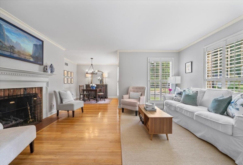 Living room with light wood-style floors, crown molding, a chandelier, and a fireplace