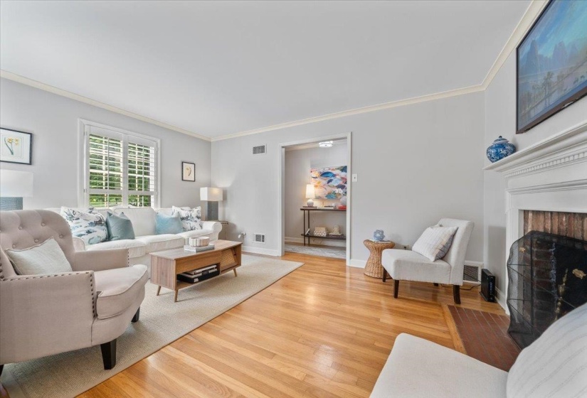 Living room featuring crown molding, wood finished floors, and a fireplace
