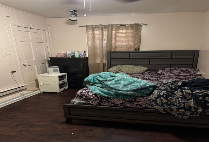 Bedroom featuring dark wood-style flooring and baseboard heating