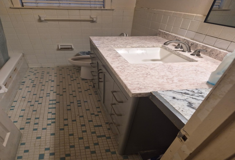 Bathroom featuring vanity, tile walls, and dark tile patterned flooring