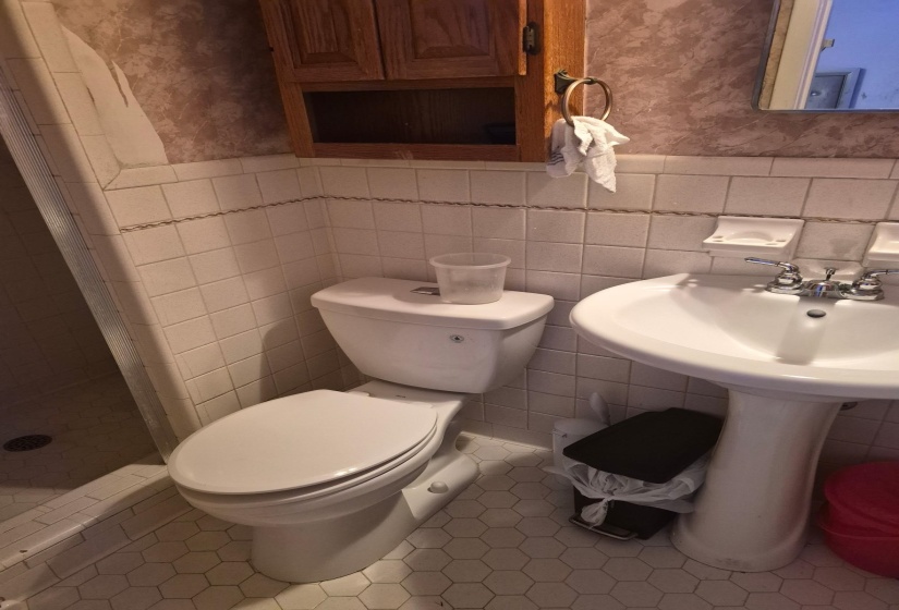 Bathroom with wallpapered walls, a stall shower, tile patterned flooring, a wainscoted wall, and tile walls