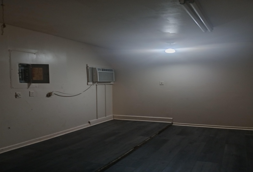 Empty room with vaulted ceiling, dark wood-style flooring, and electric panel