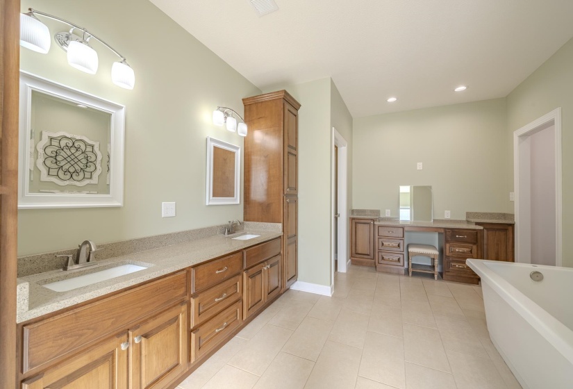 Full bathroom featuring double vanity, a freestanding tub, light tile patterned flooring, and recessed lighting