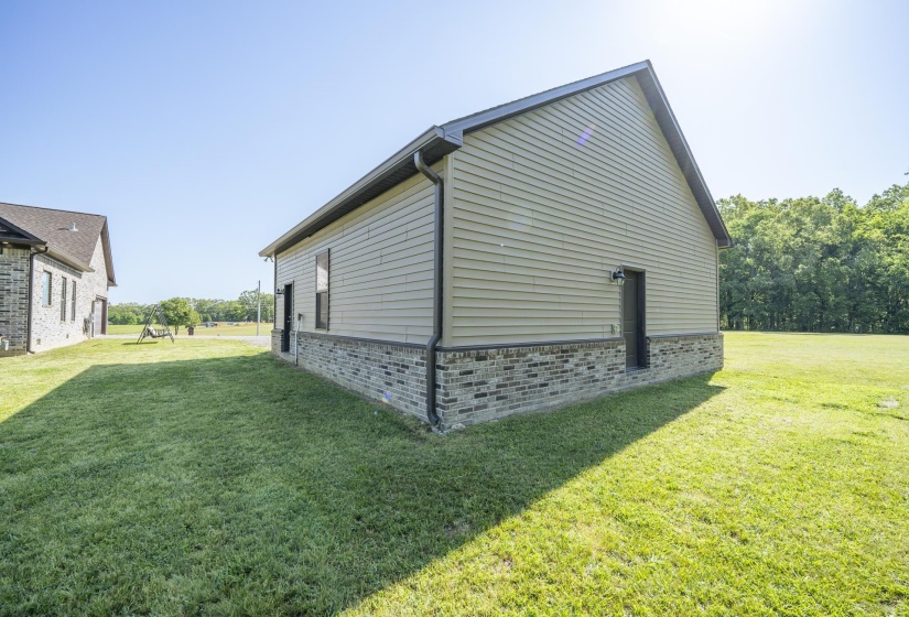 View of property exterior featuring a yard and brick siding