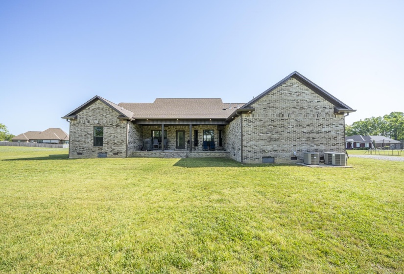 Back of property with crawl space, brick siding, a yard, and a patio