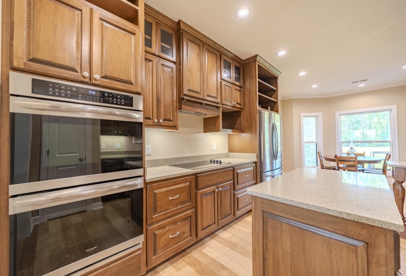 Kitchen with open shelves, stainless steel appliances, a kitchen island, glass insert cabinets, and recessed lighting