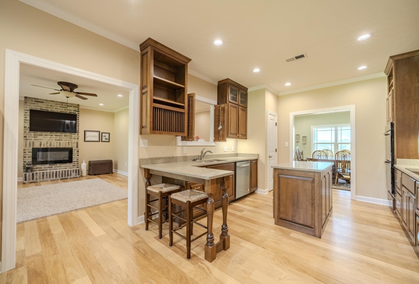 Kitchen featuring a fireplace, a center island, light wood finished floors, light stone counters, and wood finish cabinets