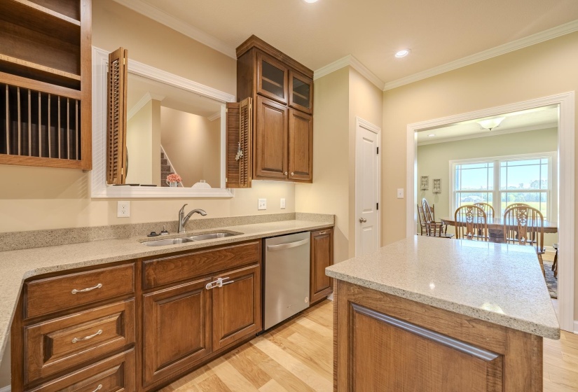 Kitchen with a center island, light wood-style floors, glass fronted cabinets, wood finish cabinets, and dishwasher