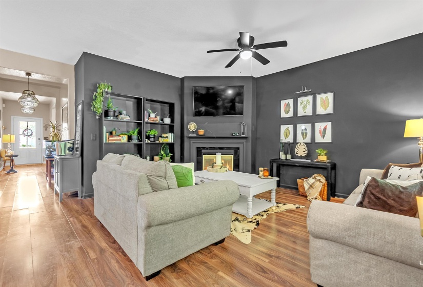 Living room with wood finished floors, a multi sided fireplace, and ceiling fan