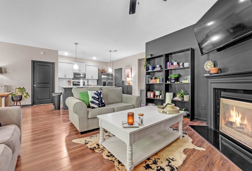 Living room featuring light wood finished floors, a glass covered fireplace, ceiling fan, and recessed lighting