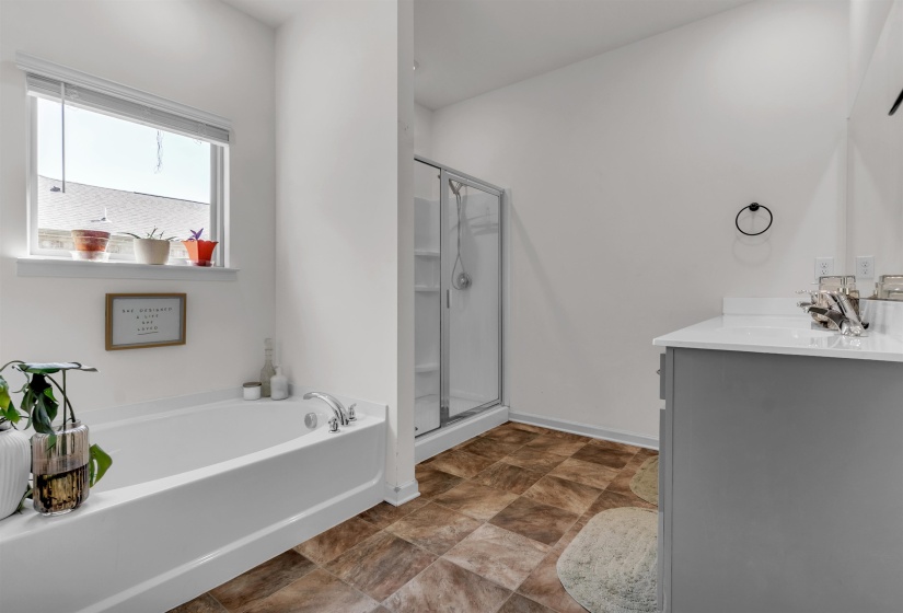 Bathroom featuring vanity, a stall shower, stone finish floors, and a garden tub
