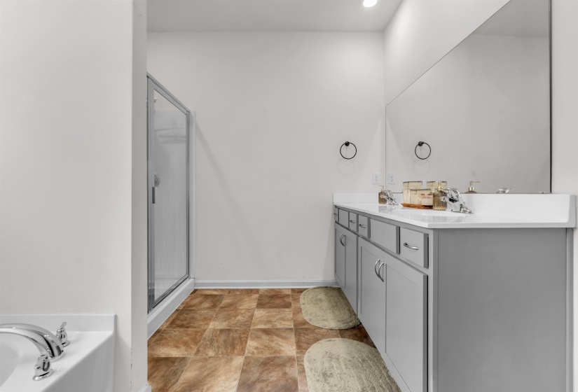 Full bath with double vanity, a shower stall, and a bath