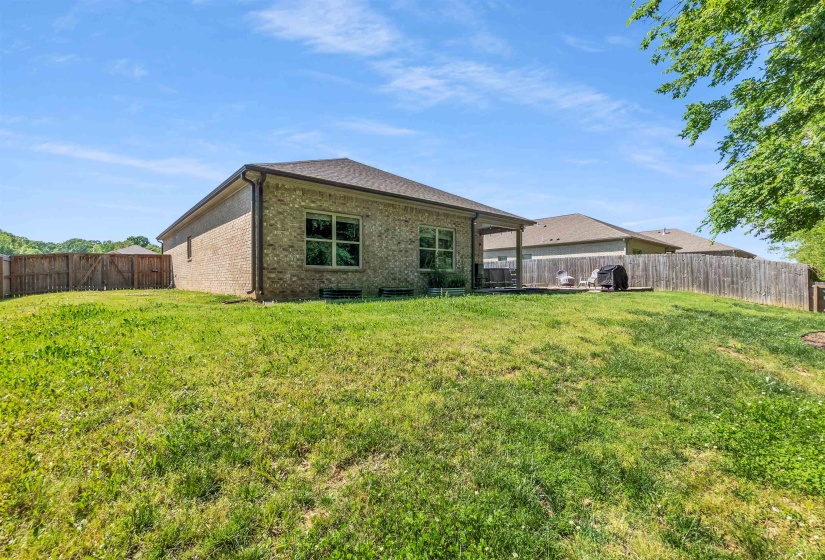 Rear view of property featuring brick siding, a fenced backyard, and a patio area