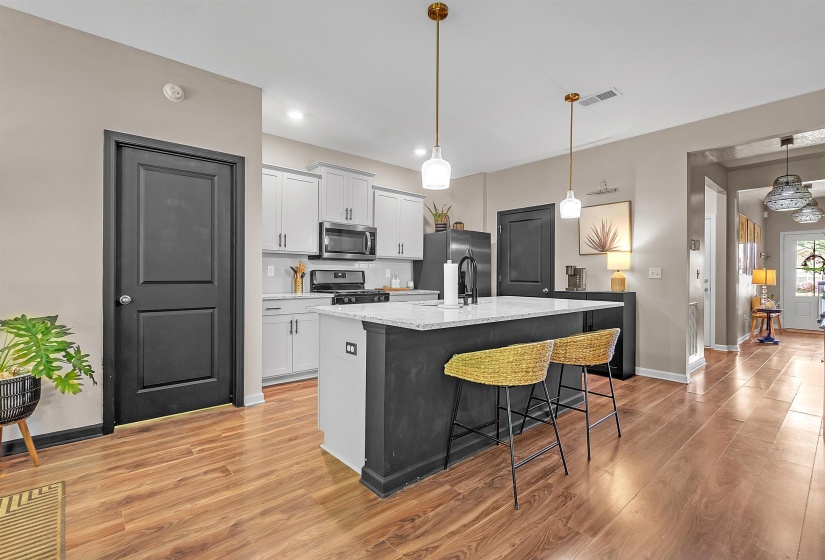 Kitchen featuring a breakfast bar, an island with sink, stainless steel appliances, light wood-type flooring, and tasteful backsplash