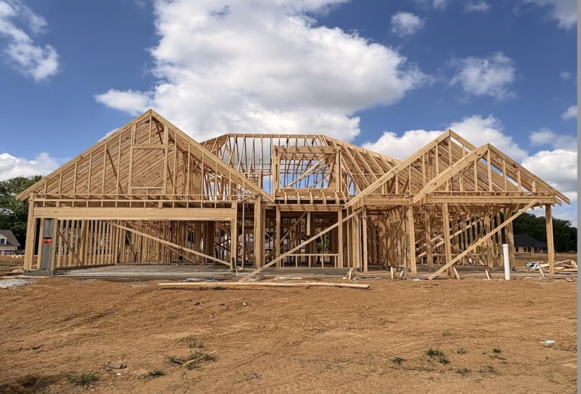New construction framing with multiple gable roof lines and a two-car garage opening